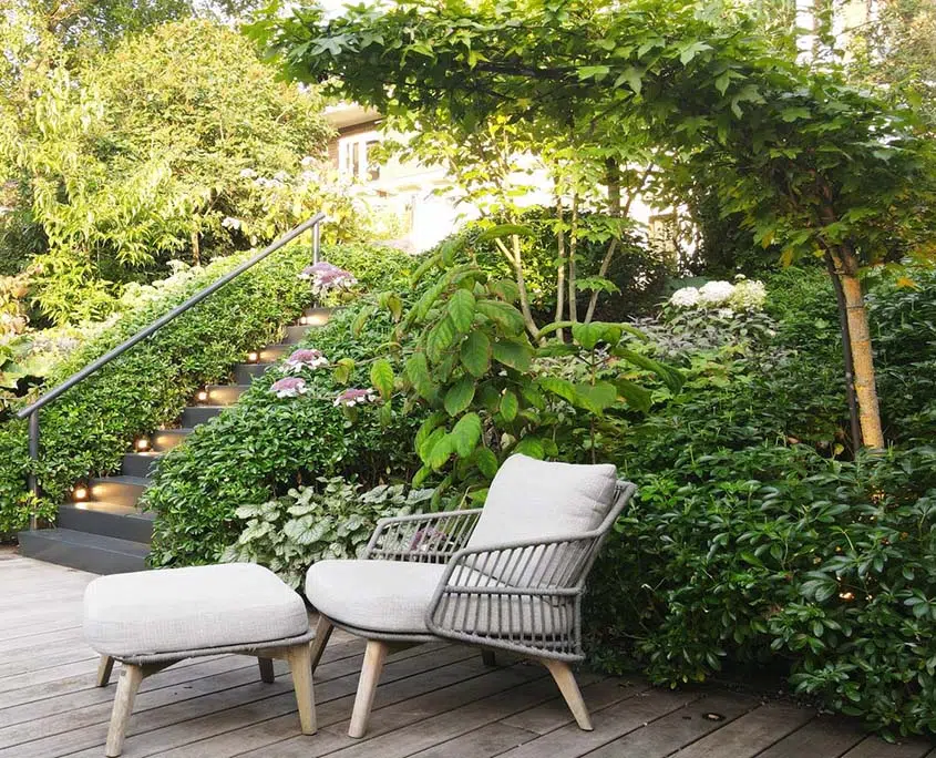 Loungestoelen onder een parasolboom in een luxe tuin in Den Bosch