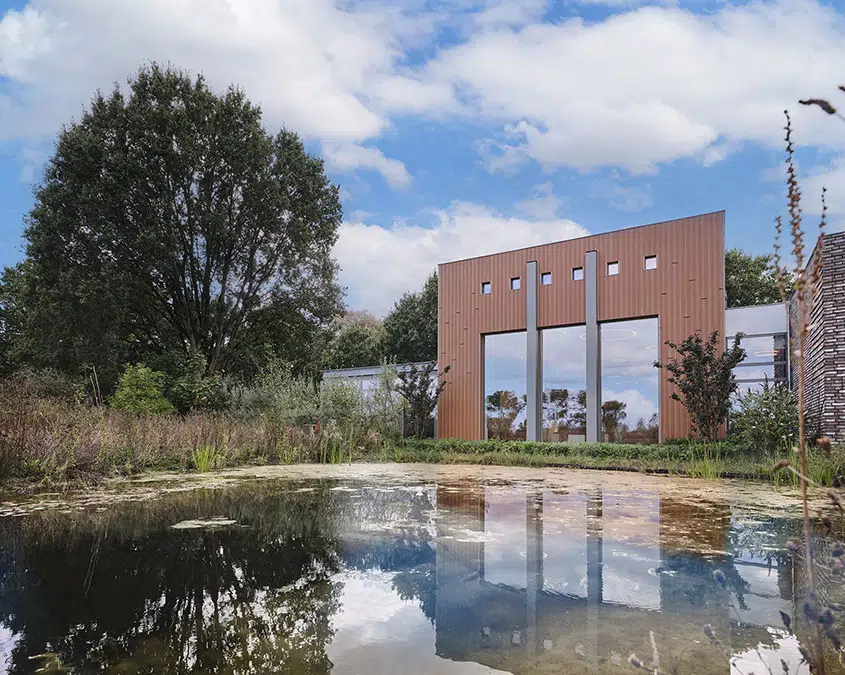 Openbaar groen met waterpartij en bomen voor een modern bakstenen gebouw